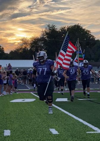 Senior Cooper Phalin leads the varsity Bulldogs onto the field carrying the American flag for Military Appreciation Night. 