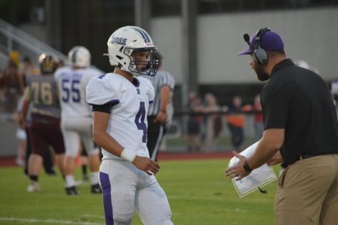 Junior Jack Ford confers with head coach Matt Griffith during the season opener. Ford is the quarterback for the varsity Bulldogs.