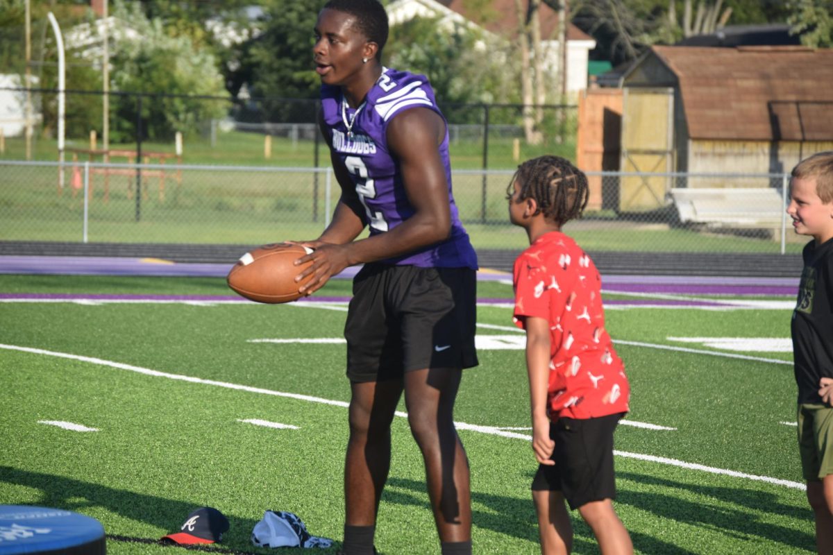 Senior Karmello Downey works with young kids during Community Night. Downey prepares to throw a ball for an elementary schooler to run and catch.