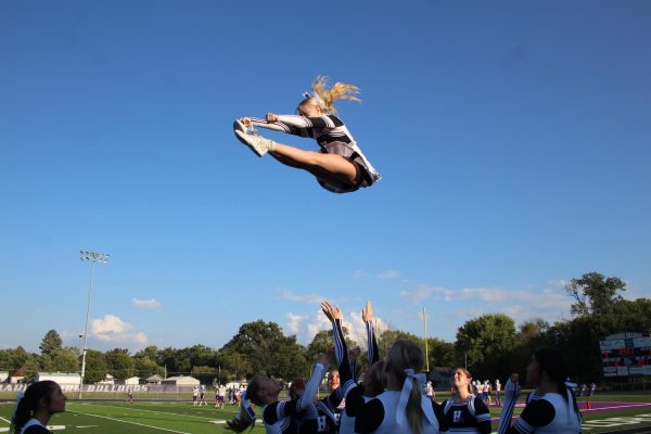 Cheerleaders toss jayla Karns into the air as she hits her pike. 