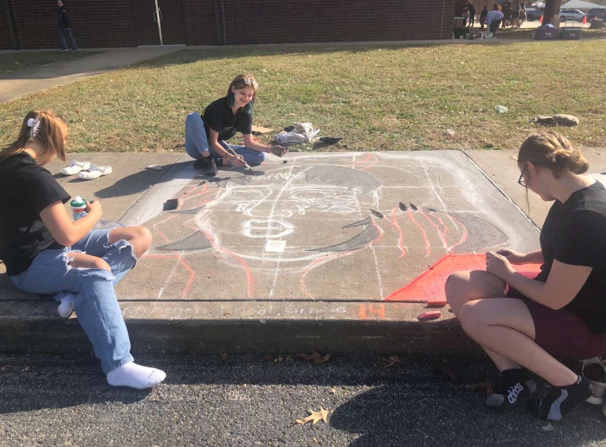 Seniors Regen Arnett, Bryleigh Lewis and sophomore Gracie Harrelson work on their piece for the annual chalk art contest Oct. 27. Senior Khoal Goodson was also a part of their group. The group won a Teachers Choice Runner up award and was the only team from Harrisburg to win an award.